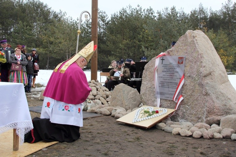 Bp Józef Zawitkowski klęczy przed pomnikiem ofiar katastrofy smoleńskiej