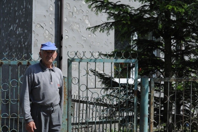 Jan Dyziak przed domem z uszkodzoną przez grad elewacją