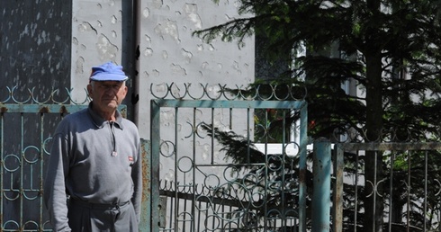 Jan Dyziak przed domem z uszkodzoną przez grad elewacją