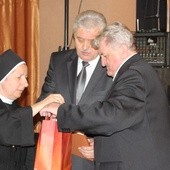 Przewodniczący Stanisław Nycz i burmistrz Marian Trela odbierają dar kard. Jaworskiego dla radnych