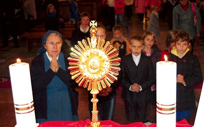 Dzieci wraz z katechetami modlą się przed relikwiami ich rówieśnika