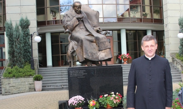Biskup nominat Roman Pindel pod pomnikiem bł. Jana Pawła II na dziedzińcu kurii w Bielsku-Białej