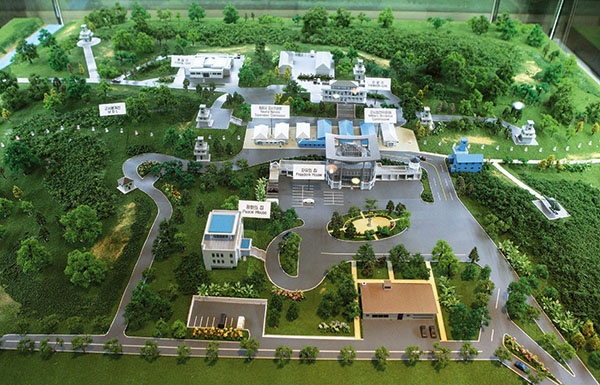 Makieta Strefy Wspólnego Bezpieczeństwa. Na samym jej środku znajduje się kilka niskich baraków. Te niebieskie administrowane są przez siły międzynarodowe, a szare przez Koreę Północną. W ich poprzek przebiega linia demarkacyjna. Formalnie więc niektóre baraki w połowie leżą na południu, a w połowie na północy Korei 