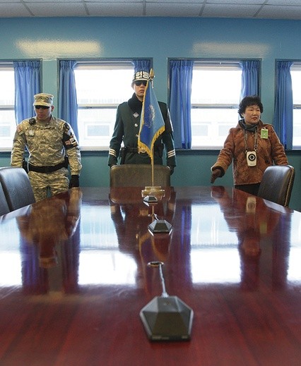 Środek jednego z baraków,  które stoją w poprzek granicy pomiędzy Koreami.  Granica biegnie dosłownie  przez połowę widocznego na zdjęciu stołu.  Po lewej stronie żołnierza południowokoreańskiego jest Korea Północna,  po prawej stronie  Południowa.  Przy tym stole odbywają się negocjacje i rozmowy dyplomatyczne  