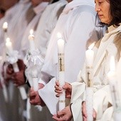 Po chrzcielnym obmyciu kandydaci zakładają alby i trwają ze świecami w ręku