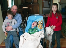 Mikołaj Lewandowski wymaga całodobowej opieki.  Na zdjęciu z tatą Krzysztofem, młodszym rodzeństwem Kaliną  i Miłoszem oraz suczką Holy 