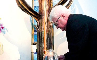 Ks. Marian Biskup zapala lampion  ogniem Miłosierdzia w łagiewnickiej kaplicy adoracji 