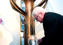Ks. Marian Biskup zapala lampion  ogniem Miłosierdzia w łagiewnickiej kaplicy adoracji 