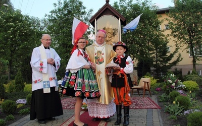 Bp Józef Zawitkowski i ks. Adam Domański oraz dzieci w strojach łowickich przy kapliczce Matki Bożej Księżnej Łowickiej