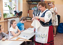 Henryka Jurałowicz-Kurzydło pokazuje dzieciom kaszubski haft