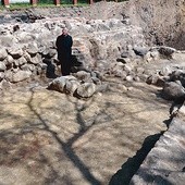 Ks. Henryk Romanik w środku odkrytego prezbiterium przy grupie kamieni, które z dużym prawdopodobieństwem są fundamentem głównego ołtarza