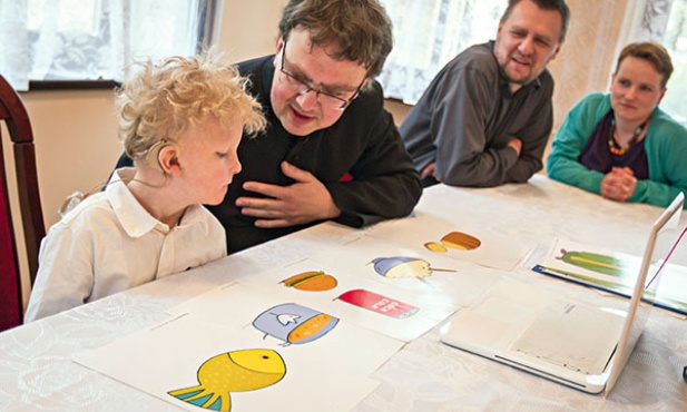 Ks. Piotr Grzesik przygotowuje Karolka do jego Pierwszej Komunii św. Z prawej strony – rodzice Karolka, Anna i Zbigniew Kasprzykowie