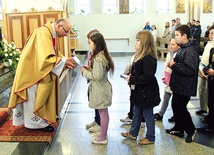  Proboszcz ks. Adam Domański przyjmuje w darze od dzieci zeszyty do religii