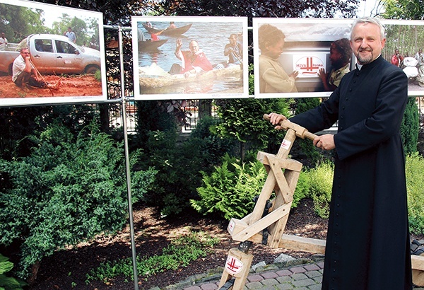 Ks. Jerzy Kraśnicki przed wystawą fotografii pojazdów kupionych dla misjonarzy 