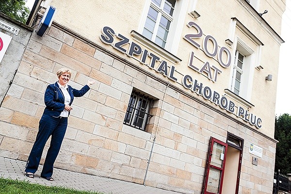  Dyrektor szpitala Joanna Niestrój-Ostrowska pokazuje neon na frontowej ścianie budynku zapraszający na obchody 200-lecia istnienia