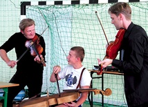 Witold Broda (po lewej) i Bartosz Izbicki uczą gimnazjalistę grać na basetli 