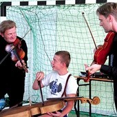 Witold Broda (po lewej) i Bartosz Izbicki uczą gimnazjalistę grać na basetli 