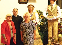  Magdalena Stancu i Halina Jach z ks. Wiesławem Kaniugą na tle dożynkowej dekoracji