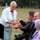 Starościna dożynek Bożena Furmańska zachęca do skosztowania chleba i miodu