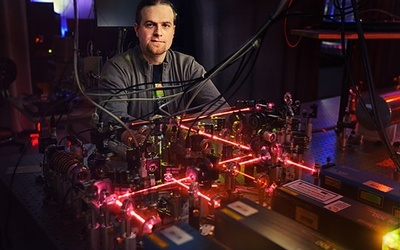 Radosław Chrapkiewicz jest doktorantem Wydziału Fizyki Uniwersytetu Warszawskiego i współautorem tego układu atomowej pamięci kwantowej. Co to takiego? W największym skrócie krótkotrwała pamięć, w której widoczne wiązki lasera mają podobną funkcję do igły magnetycznej w twardym dysku komputera