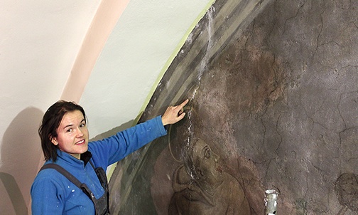  Sylwia Kudła pokazuje pęknięcia na nieoczyszczonej jeszcze części fresku 