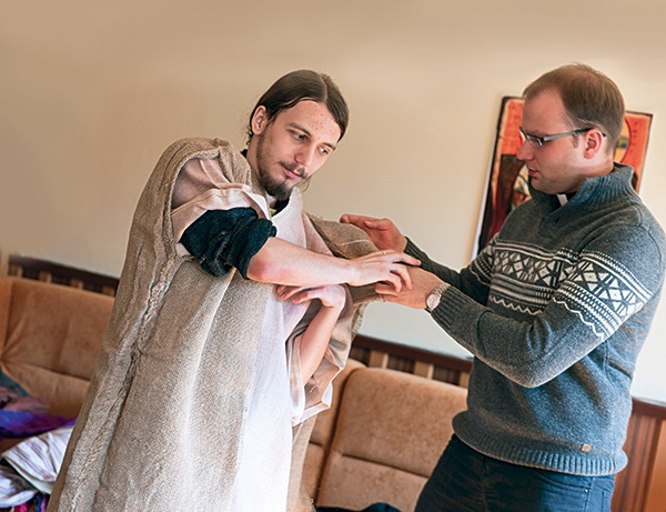 Ks. Adam Zgodzaj,  opiekun całego przedsięwzięcia, pomaga Bartłomiejowi Drobczykowi przywdziać  szatę Jezusa