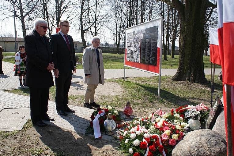 Od lewej Włodzimierz Fetliński, Maciej Małecki i Bartosz Fetliński przed tablicą upamiętniającą ofiary katastrofy smoleńskiej 