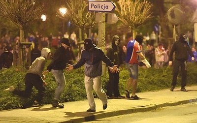 3.05.2015. Knurów. Polska. Pseudokibice rzucają niebezpiecznymi przedmiotami w kierunku policji ochraniającej komisariat. W sobotę 2 maja podczas meczu piłki nożnej między Concordią i Ruchem Radzionków doszło do zamieszek, w trakcie których jeden z kibiców został postrzelony przez policjanta z broni gładkolufowej. Ranny zmarł w szpitalu. W nocy z 2 na 3 maja doszło do starć pseudokibiców z policją przed szpitalem i komisariatem policji w Knurowie. 