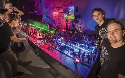 „Łapacze fotonów”, młodzi fizycy z UW, na tym zdjęciu zachowują się jak fotony. Są w dwóch miejscach równocześnie. Obok układu pomiarowego Radosław Chrapkiewicz (po prawej) oraz Michał Jachura (stojący za nim) 