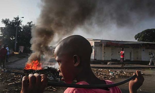 29.05.2015. Burundi, Bużumbura. Burundyjski chłopak obok płonących barykad podczas antyrządowej demonstracji przeciwko prezydentowi. Pierre Nkurunziza kandyduje po raz trzeci w wyborach na ten urząd, co budzi zastrzeżenia opozycji.