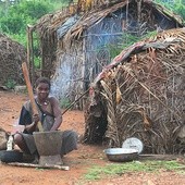 Pigmejka przed swoją chatą z palmowych liści i patyków. Właśnie ubija maniok, z którego przygotuje posiłek foto Beata Zajączkowska