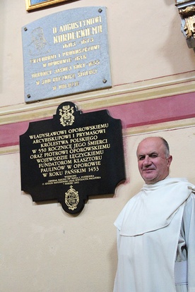 O. Czesław Matras w oporowskim kościele, nad nim tablica upamiętniająca o. Augustyna Kordeckiego