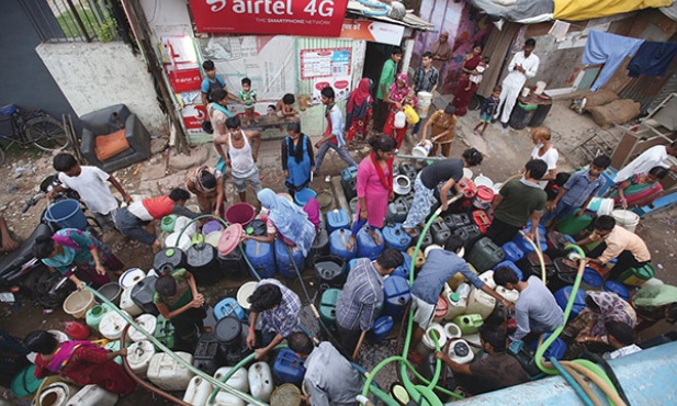 30 lipca 2015. Indie. New Delhi. Mieszkańcy miasta napełniają kontenery wodą konieczną do życia. Około 20 proc. ludności nie ma dostępu do bieżącej wody i jest zmuszona korzystać z tej dostarczanej przez cysterny. Raporty mówią, że dziennie w New Delhi brakuje ok. 750 milionów litrów wody. 