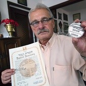 Andrzej Głowacki pokazuje dyplom i medal Sprawiedliwy wśród Narodów Świata przyznany jego ojcu