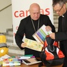 Bp Piotr Greger pakuje do plecaka Caritas zakupioną przez siebie szkolną wyprawkę