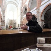 Ks. Piotr Nowak ze znaczkiem promującym tumską archikolegiate