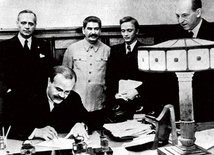 Wiaczesław Mołotow składa podpis pod paktem o nieagresji pomiędzy Związkiem Sowieckim a Trzecią Rzeszą. Joachim von Ribbentrop stoi za nim, obok Stalina