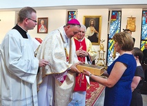 Parafianie składają w darze ołtarza pustą księgę na zapisywanie nowych łask wyproszonych przez Maryję