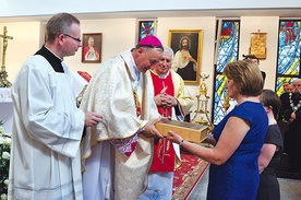 Parafianie składają w darze ołtarza pustą księgę na zapisywanie nowych łask wyproszonych przez Maryję