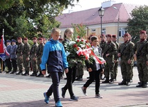 Delegacja uczniów niesie wiązankę kwiatów pod pomnik na pl. Kościuszki