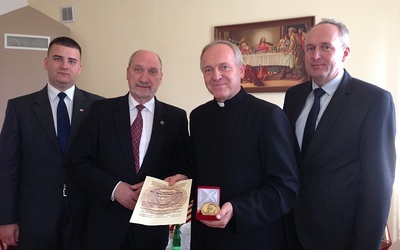Ks. Bogumił Karp z przyznanym medalem. Po jego prawej Antoni Macierewicz, po lewej Dariusz Misztal, burmistrz Rawy Mazowieckiej