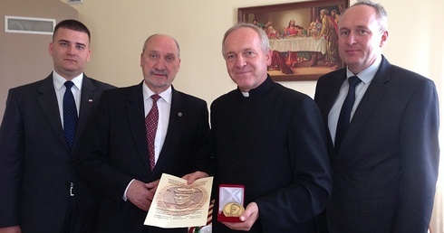 Ks. Bogumił Karp z przyznanym medalem. Po jego prawej Antoni Macierewicz, po lewej Dariusz Misztal, burmistrz Rawy Mazowieckiej