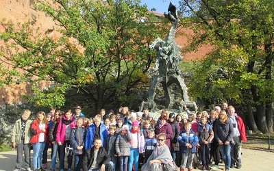Uczestnicy wycieczki przy rzeźbie smoka wawelskiego w Krakowie