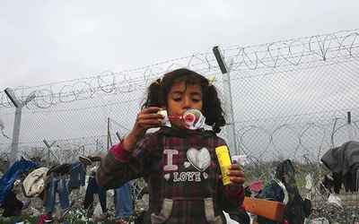  17.03.2016. Grecja. Dziewczynka, imigrantka z Syrii, puszcza bańki mydlane tuż przy ogrodzeniu obozu dla uchodźców.