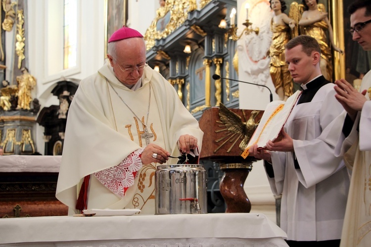 Bp Andrzej F. Dziuba wlewa wonny balsam do naczynia z olejem