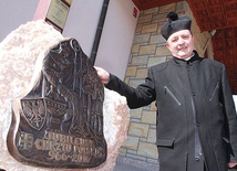 Ks. Marian Stach obok kamienia z płaskorzeźbą, będącą materialną pamiątką rocznicy chrztu Polski