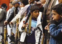 Jemeński chłopak z bronią obok grupy wspierającej szyickich rebeliantów Huti, kontrolujących Sanę oraz terytoria na północy i zachodzie kraju. 21.04.2016 Jemen. Sana.