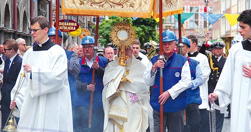 Abp Sławoj Leszek Głódź niesie Najświętszy Sakrament podczas procesji.