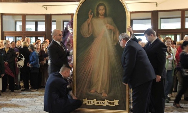 Mężczyźni wnoszą obraz Jezusa Miłosiernego do kościoła