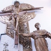 Św. Antoni wskazuje zarazem na ołtarz i na krzyż.  Pod tą kompozycją stoi chrzcielnica.